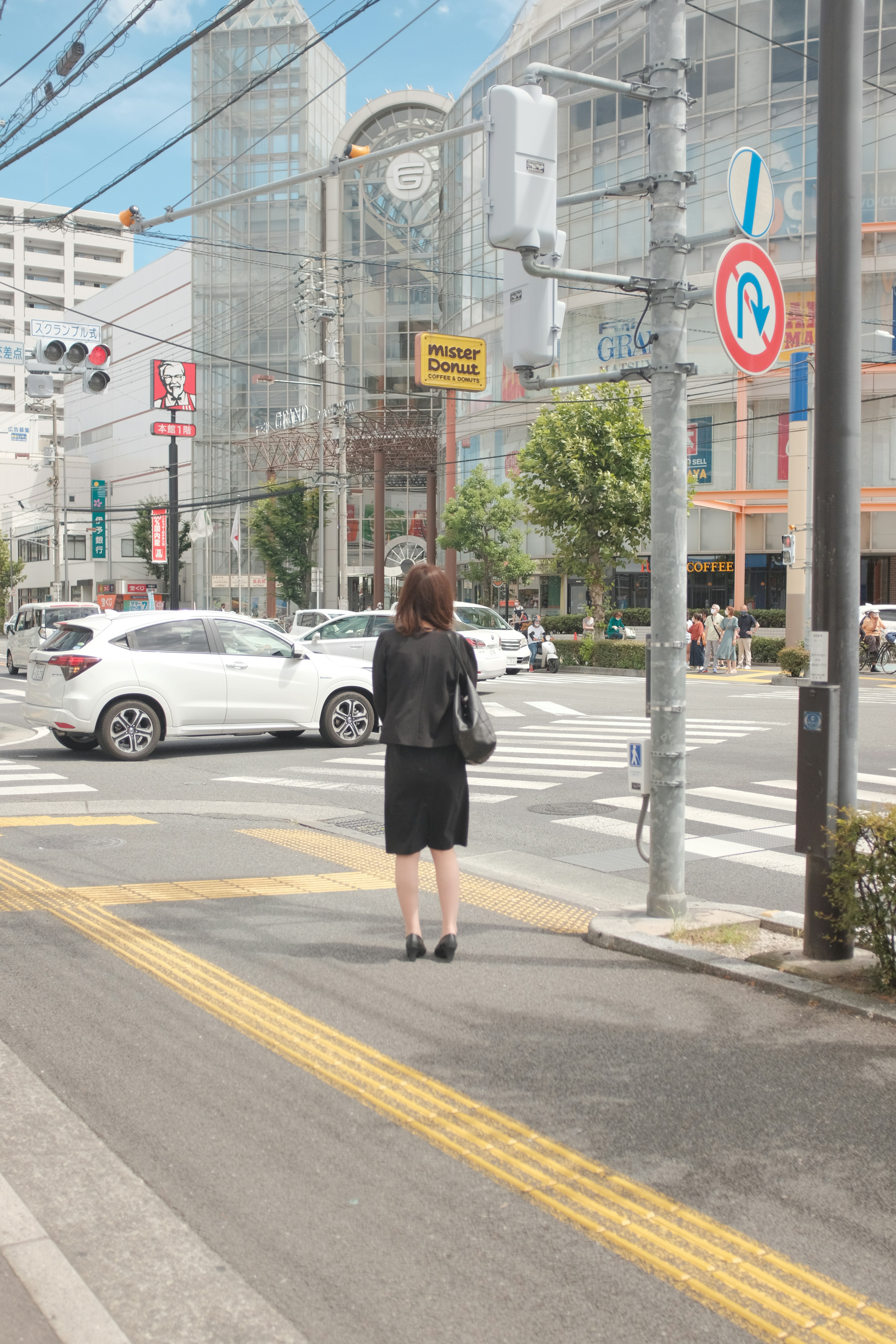 woman in black jacket walking on pedestrian lane during daytime